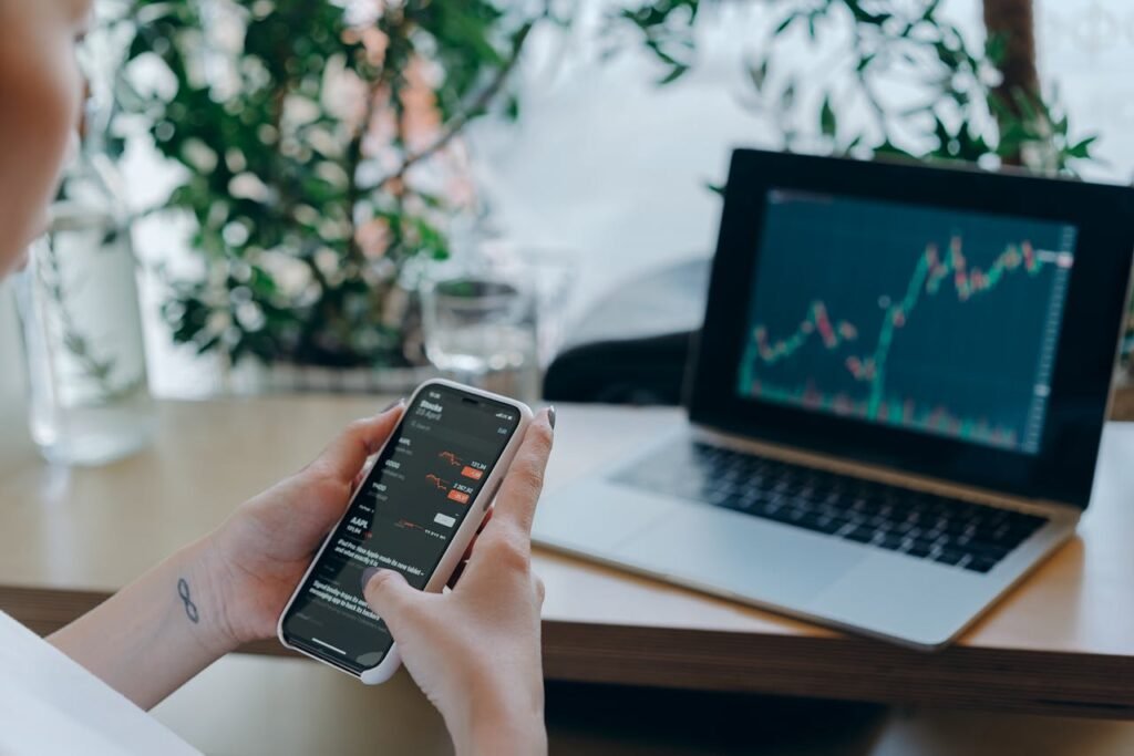 pexels-photo-7681670 Businesswoman reviewing financial data on smartphone alongside laptop displaying graphs in modern workspace.